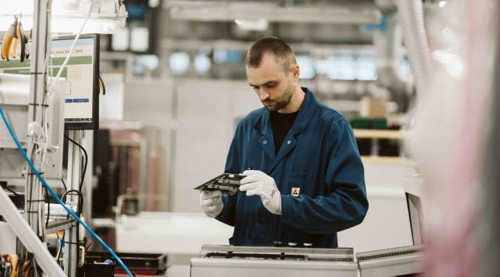 Operator ASSEL kontroluje zmontowaną płytkę PCBA przy stanowisku z terminalem MES na hali produkcyjnej